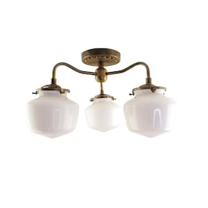 May include: A vintage-style ceiling light fixture with three white glass shades. The fixture has a bronze-colored metal frame and a decorative ceiling mount. The shades are a classic, rounded shape, and the overall design is reminiscent of early 20th-century lighting.