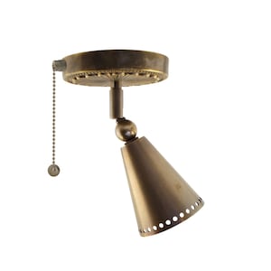 May include: A vintage-style brass spotlight fixture. The fixture has a circular base with a decorative edge, a ball joint, and a cone-shaped light. A chain with a small ball hangs from the base.