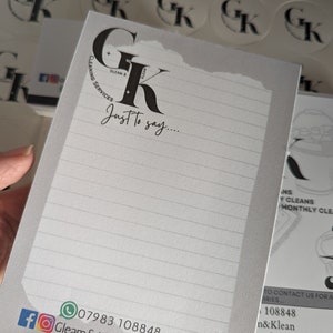 May include: A white notepad with a black logo that says "Gleam & Klean Cleaning Services" and the text "Just to say..."  The notepad has a lined background and a phone number and social media icons at the bottom.