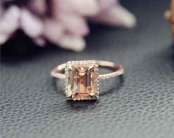 Könnte beinhalten: Ein Verlobungsring aus Roségold mit einem großen, rechteckigen, hellpfirsichfarbenen Edelstein, der von einem Heiligenschein aus kleineren Diamanten umgeben ist. Die Ringschiene ist ebenfalls mit kleineren Diamanten besetzt.