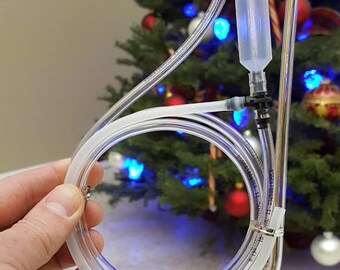 May include: A clear plastic tube with a clear plastic bulb on the end. The tube is bent into a loop and is held in a hand. The tube is likely used for a water bottle or other beverage container.