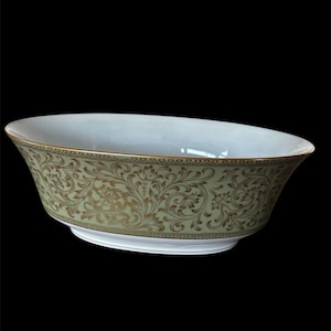May include: An oval-shaped serving bowl with a white interior and a pale green exterior adorned with a gold floral pattern. The rim and base feature gold trim. The bowl is set against a black background.