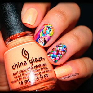 May include: A close-up of a bottle of China Glaze nail polish in a peach color with a black and silver label. The bottle is sitting in front of a hand with colorful nail art. The nail art features a colorful abstract design on one nail and a plaid design on another nail.