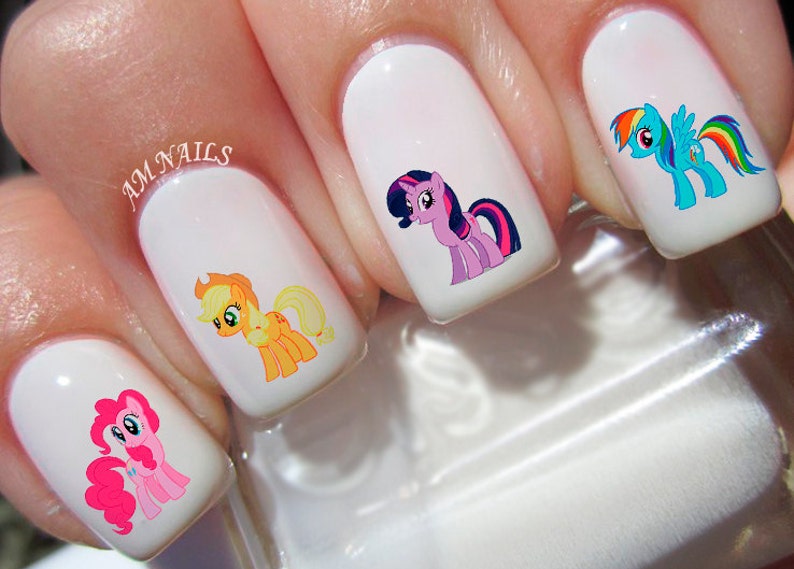 May include: Five white fingernails with My Little Pony nail art. The ponies are Pinkie Pie, Applejack, Twilight Sparkle, Rainbow Dash, and Fluttershy.