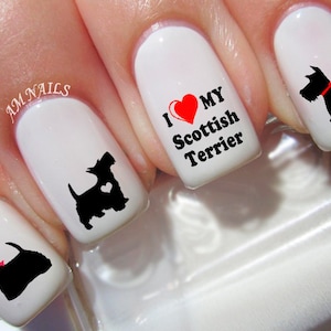 May include: White nail polish base with black Scottish Terrier silhouettes, some featuring small red bows or heart cutouts. One nail displays the red heart graphic and black text reading I LOVE MY SCOTTISH TERRIER. The text AM NAILS is visible.