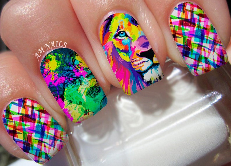 May include: Close-up of five fingernails with colorful nail art designs. One nail features a colorful lion's face, another has a colorful abstract design, and the other three have a colorful plaid design. The text "AM NAILS" is visible on one of the nails.