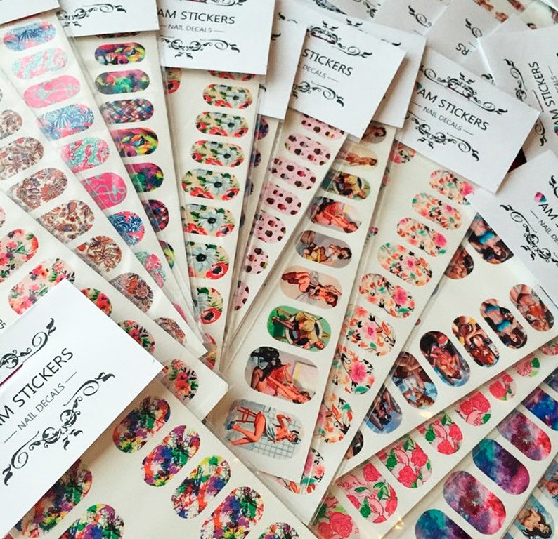 May include: Assortment of nail stickers with various designs, including floral patterns, pin-up girls, and abstract art. The stickers are packaged in clear plastic bags with white labels that read "MAM STICKERS - NAIL DECALS".
