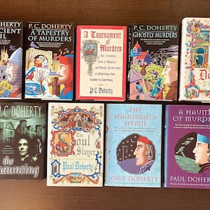 May include: A collection of paperback books with colorful covers. Titles include "An Ancient Evil," "A Tapestry of Murders," and "The Hangman's Hymn." The books are by authors P.C. Doherty and Paul Doherty.