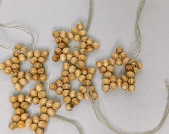 Op de afbeelding: Vier houten sterornamenten met een natuurlijke houten afwerking en een touwtje om op te hangen.
