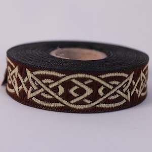 Peut inclure: Garniture brune et dor&eacute;e avec un motif de n&oelig;ud celtique. La garniture est enroul&eacute;e sur une bobine.