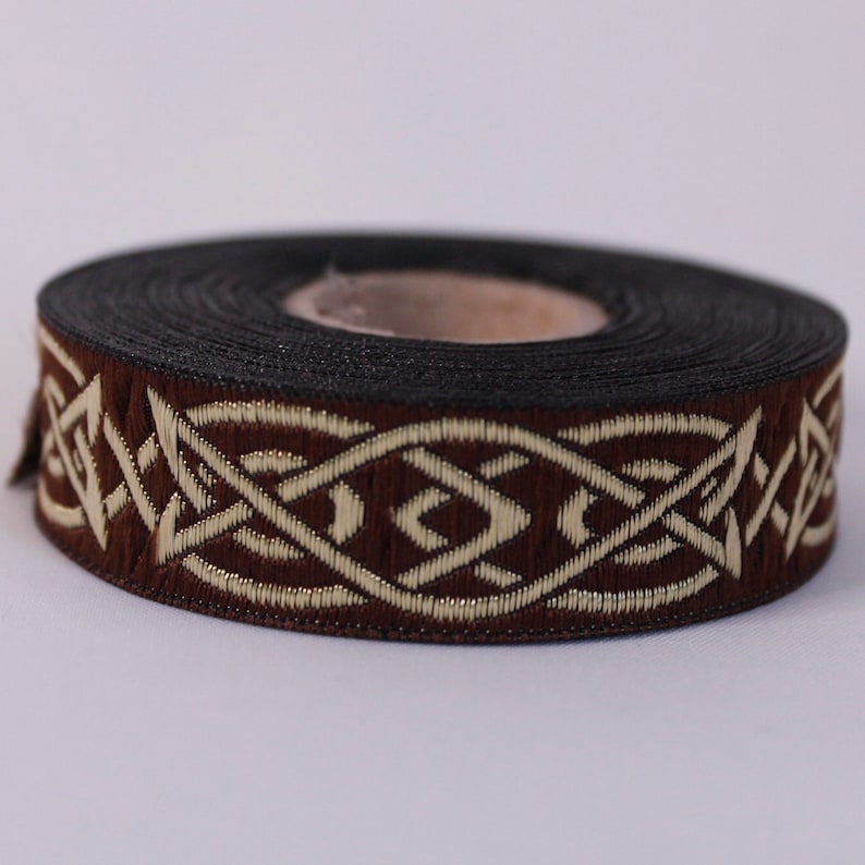 Peut inclure: Garniture brune et dor&eacute;e avec un motif de n&oelig;ud celtique. La garniture est enroul&eacute;e sur une bobine.