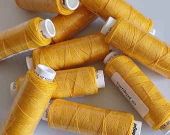 Pode incluir: Um close-up de um monte de carretéis de fio amarelo. Os carretéis são etiquetados com "Knoflíková nit" e "hagal".