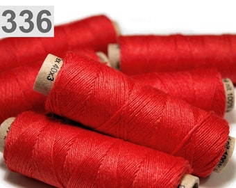 Pode incluir: Close-up de carretéis de fio vermelho. Os carretéis são feitos de cartão e têm um rótulo que diz "EX04 100%"