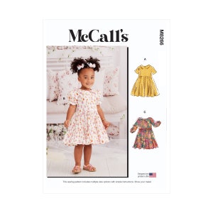Könnte beinhalten: Nähmuster McCall's M8266 für ein Mädchenkleid. Das Muster enthält drei verschiedene Ansichten: ein kurzärmliges Kleid mit Peter-Pan-Kragen, ein kurzärmliges Kleid mit Rundhalsausschnitt und ein langärmliges Kleid mit Rundhalsausschnitt. Das Muster wurde in den USA entworfen und gedruckt.