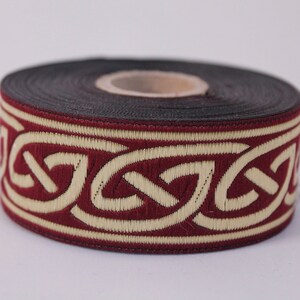 May include: A roll of burgundy and cream colored trim with a Celtic knot design.