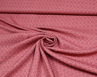 May include: A close-up of a pink fabric with a small, dark grey geometric pattern. The fabric is folded and draped, showing its texture.