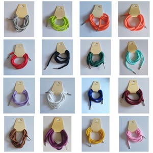May include: A collection of colorful shoelaces in various hues, including gray, green, orange, red, black, teal, purple, white, blue, brown, magenta, yellow, and pink. Each pair is neatly coiled and attached to a tan cardboard tag.