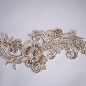 Könnte beinhalten: Beigefarbener floraler Spitzenbesatz mit einem zarten Design mit filigranen Schnörkeln und Perlenakzenten.