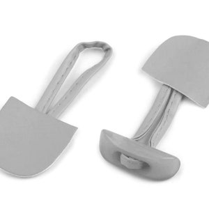 Könnte beinhalten: Zwei graue Leder-Toggle-Verschlüsse mit einer Schlaufe zum Anbringen an einem Kleidungsstück. Die Toggle sind halbkreisförmig und haben eine genähte Naht.