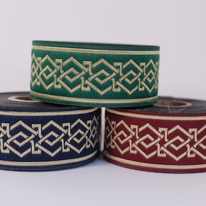 Può includere: Tre rotoli di passamaneria decorativa con un motivo geometrico. La passamaneria è verde, blu navy e bordeaux con accenti dorati.
