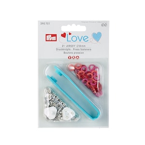 Può includere: Un pacchetto di 21 bottoni a pressione argentati da 8 mm con uno strumento blu per fissarli. Il pacchetto ha un cuore rosa con la parola "Love" su di esso.