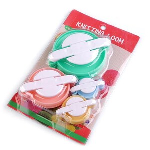 May include: A set of four colorful plastic knitting looms in a clear plastic package. The package has the words "Knitting Loom" printed on it. The looms are green, pink, blue, and yellow.