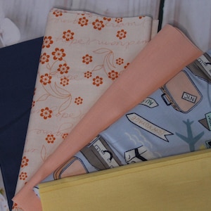 Könnte beinhalten: Vier Stoffmuster, eines mit einem floralen Muster in Orange und Weiß, eines in Pfirsichfarbe, eines mit blauem Hintergrund und einem Reisemotiv mit Koffern und Flugzeugen und eines in einfarbiger gelber Farbe.