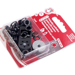 Può includere: Un pacchetto di occhielli in metallo nero con rondelle, in un contenitore di plastica trasparente. La confezione è etichettata con il testo "Occhielli con rondelle" e "Ø 10 mm".