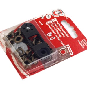 Può includere: Un pacchetto di occhielli in ottone da 10 mm con rondelle. La confezione include uno strumento per l'installazione degli occhielli. La confezione è rossa e bianca con testo in ceco, inglese, tedesco e russo.