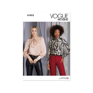 Op de afbeelding: Vogue Patterns naaipatroon voor een blouse met strik. Het patroon toont twee modellen die verschillende versies van de blouse dragen. Een model draagt een effen roze blouse met een zwarte riem en een zwarte broek. Het andere model draagt een zwart-wit gebloemde blouse met een zwarte riem en een rode broek. Het patroonnummer is V1973.