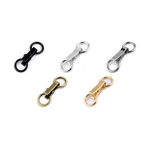 Può includere: Quattro moschettoni girevoli in diverse finiture: nero, argento, ottone anticato e oro. Ogni moschettone ha due anelli.