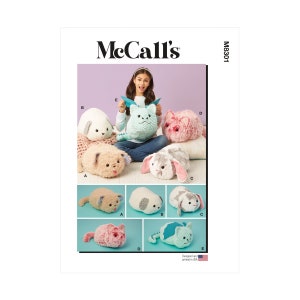 Op de afbeelding: Een naaipatroon voor het maken van pluche speelgoed. Het patroon bevat instructies voor het maken van verschillende dieren, waaronder een draak, een kat, een hond en een konijn. Het patroon is van McCall's en heeft nummer M8301.