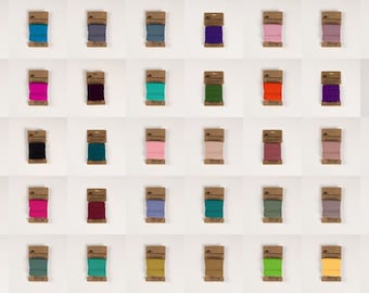 Pode incluir: Conjunto de 45 carretéis de fio colorido em vários tons de vermelho, rosa, azul, verde, roxo, laranja, amarelo, marrom, cinza e branco. Cada carretel é embalado em um invólucro de papel marrom com um rótulo.