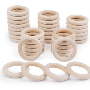 May include: A set of wooden rings, stacked in different sizes and arranged in a pattern. The rings are natural wood colour and have a smooth, polished finish.