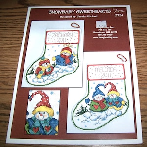 May include: Cross stitch pattern for two snowbaby stocking ornaments. The pattern includes the names "Zackary 2011" and "Melinda 2011".