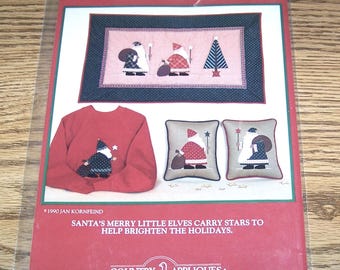 May include: A red and white Christmas applique pattern featuring jolly old elves carrying stars to Santa. The pattern includes a pillow, a sweater, and a wall hanging. The pattern is titled "Jolly Old Elves" and is by Country Appliques.