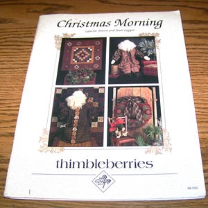 May include: A white booklet titled "Christmas Morning" by Lynette Jensen and Joan Lepper. The cover features four images of Christmas-themed crafts, including a quilt, doll, and wreath. The "thimbleberries" logo is at the bottom.