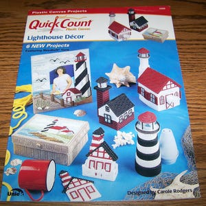May include: A craft instruction booklet titled Quick Count Plastic Canvas Lighthouse Décor featuring six projects. The cover displays various plastic canvas lighthouse-themed items, including a picture frame, a box, and several lighthouse models.