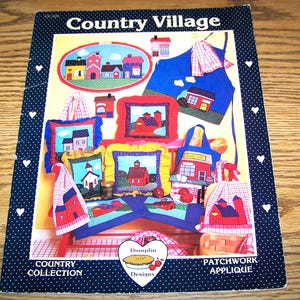 May include: A book of patchwork applique patterns featuring a country village theme. The cover shows a variety of projects including a pillow, an apron, a tote bag, and a wall hanging. The book is titled "Country Village" and is by "Dumplin Designs".