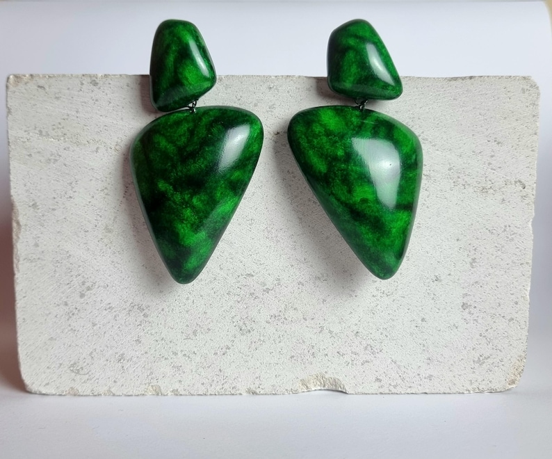 May include: A pair of drop earrings featuring two distinct pieces each, with a smooth, polished finish. The earrings display a vibrant emerald green color with dark, marbled, vein-like patterns throughout the surface of the geometric shapes.