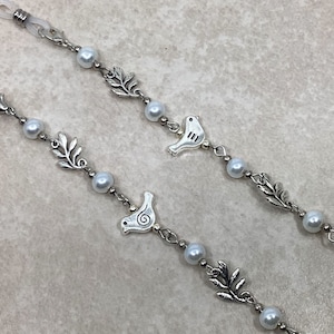 May include: Two silver eyeglass chains with white pearl beads and silver bird charms. Each chain has a silver leaf charm between the beads.