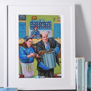 May include: A framed print featuring a colorful illustration of a kitchen scene. Two people in blue uniforms are near a large pot. The text "DUNDEE AWARDS 5-7" is visible. The text "TWO THANGS" is also visible.