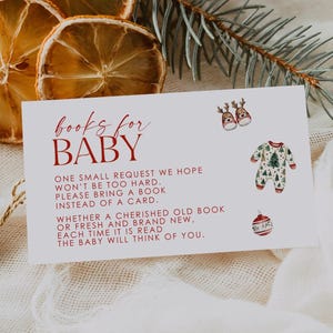 Pode incluir: Um cartão de convite para chá de bebé com o texto "books for BABY" em vermelho. O cartão inclui um pedido para trazer um livro em vez de um cartão, com ilustrações festivas de um macacão, enfeites e renas. Fatias de laranja secas e vegetação no fundo.