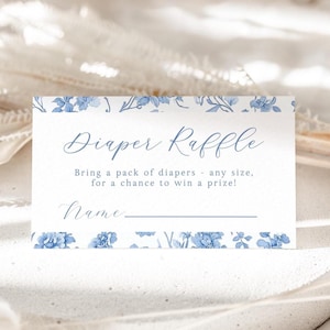 May include: A white card with blue floral accents and the text "Diaper Raffle." The card reads "Bring a pack of diapers - any size, for a chance to win a prize!" and includes a line for a name.
