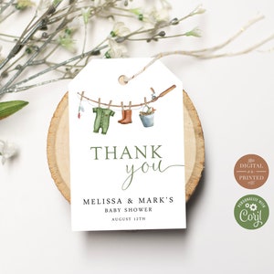 Op de afbeelding: Een wit bedankkaartje met groene tekst die "Bedankt" en "Baby Shower van Melissa & Mark op 12 augustus" zegt. Het kaartje heeft een aquarel-illustratie van een waslijn met een baby-romper, laarzen en een emmer die eraan hangen.