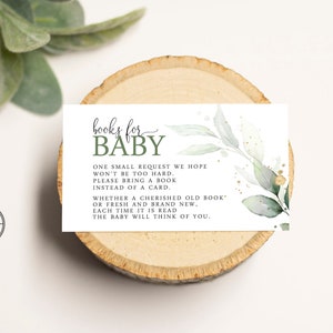 May include: A white card with green leaves and gold glitter. The text on the card reads "books for baby. One small request we hope won't be too hard. Please bring a book instead of a card. Whether a cherished old book or fresh and brand new, each time it is read the baby will think of you."