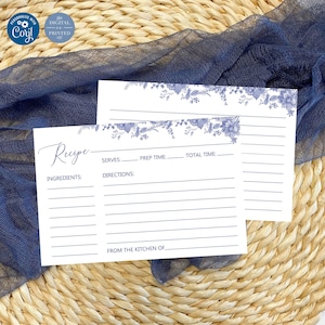 May include: Two white recipe cards with blue floral borders. The top card has the word "Recipe" written in cursive. The bottom card has the words "Ingredients", "Serves", "Prep Time", "Total Time", "Directions", and "From the Kitchen Of" printed on it.