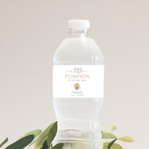 May include: A white water bottle with a label that says "a little PUMPKIN is on the way!" with a small pumpkin illustration and the text "Annabelle's Baby Shower".