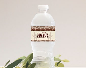 May include: A clear plastic water bottle with a brown and tan label that says "A Little Cowboy Is On His Way!" The label has a brown and tan camouflage pattern with cactus silhouettes.