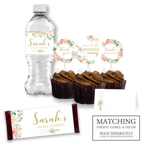 May include: A set of bridal shower party decorations featuring a floral and gold design with the name "Sarah's" and the text "Bridal Shower". The set includes a water bottle label, cupcake toppers, a chocolate bar wrapper, and place cards.